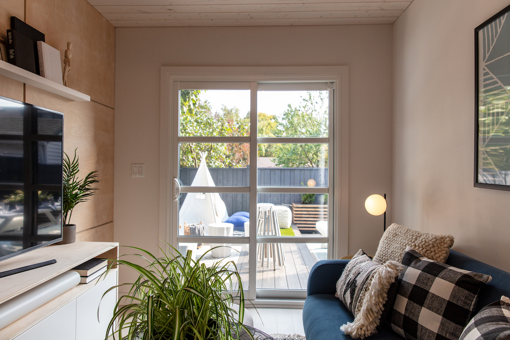 converted garage lounge space with couch, televeition and glass doors