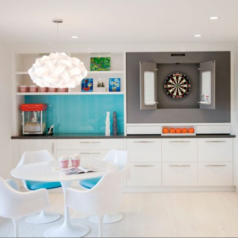 Unique chandelier hanging over the dinner table in a white basement kitchen