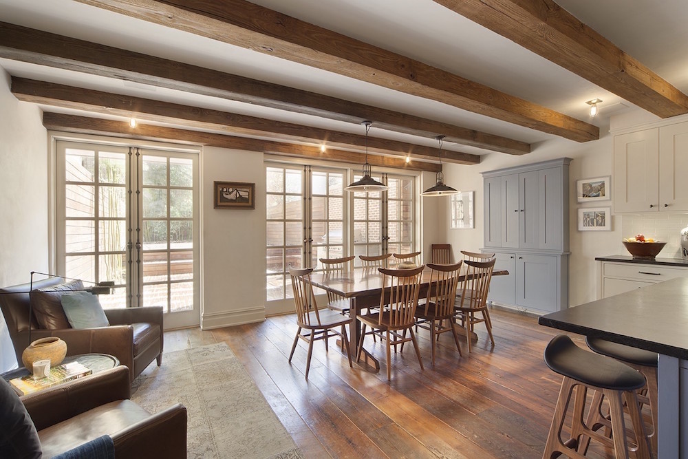 white dining room with wooden table and chairs and exposed beams