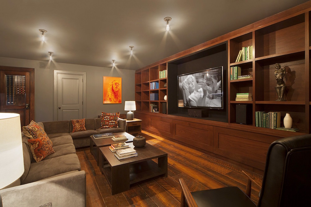 finished basement with built-in shelves and television and grey walls