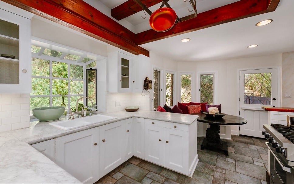 white kitchen with marble countertops and rustic stone flooring