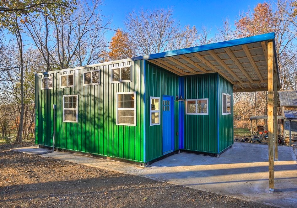 Bright green storage container home in a wooded area