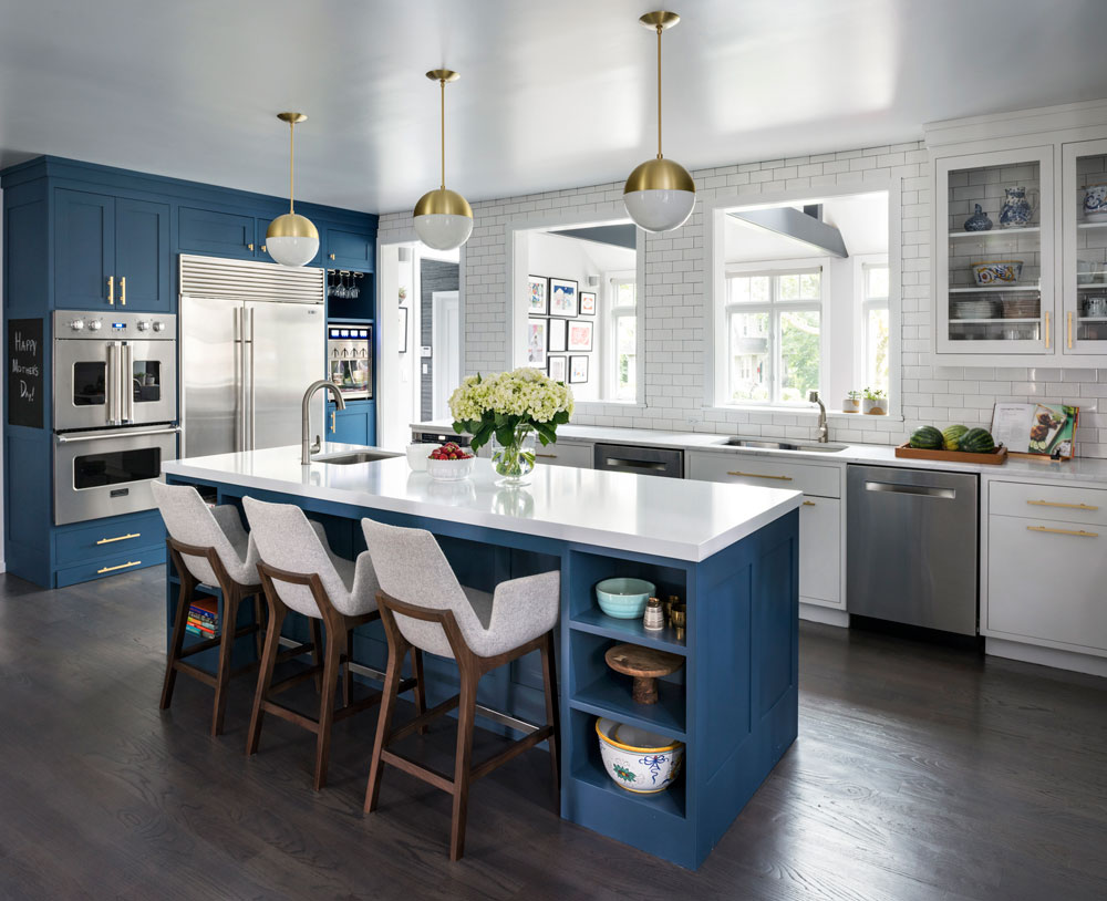 Modern blue and white kitchen with brass pulls, matching orb pendants and subway tile backsplash.