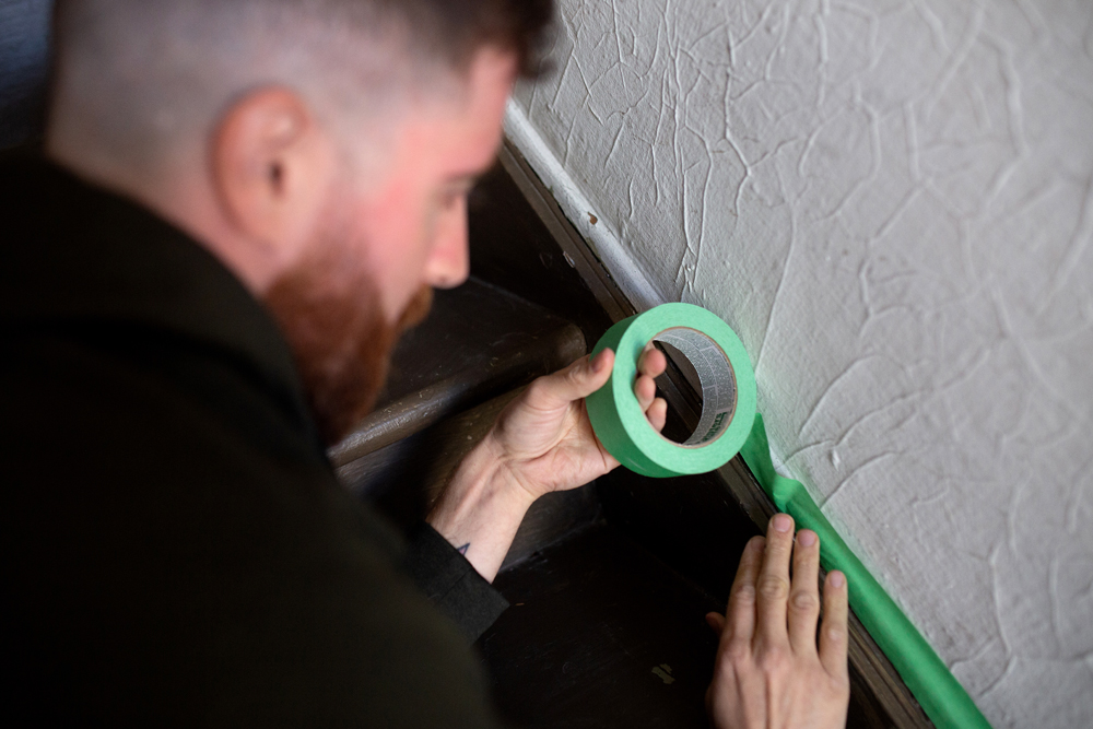 Putting painter's tape on old stairs before painting them