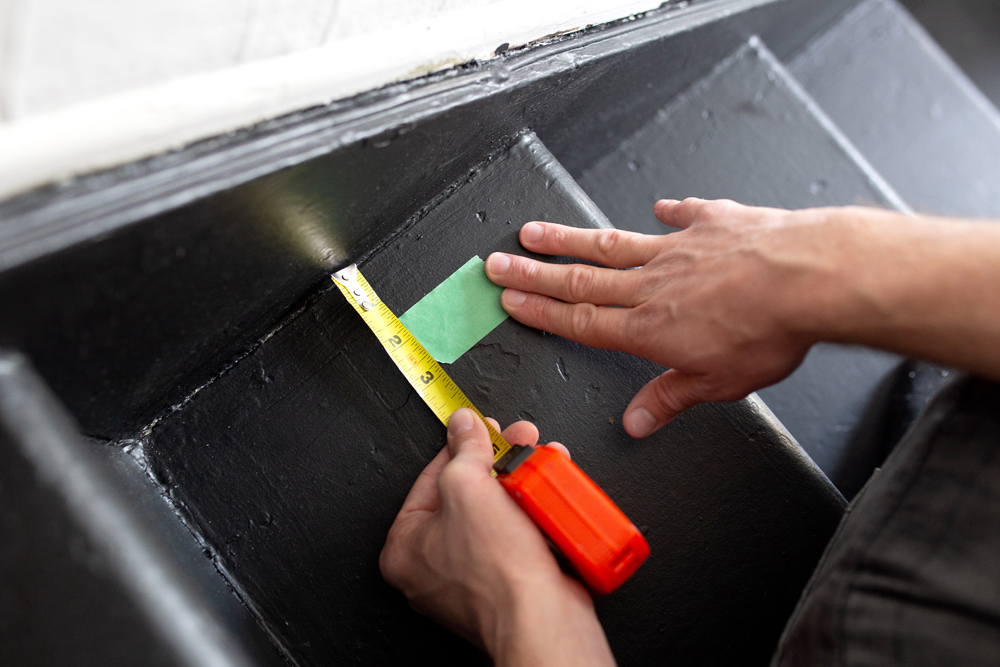 Putting painter's tape on old stairs before a DIY reno project