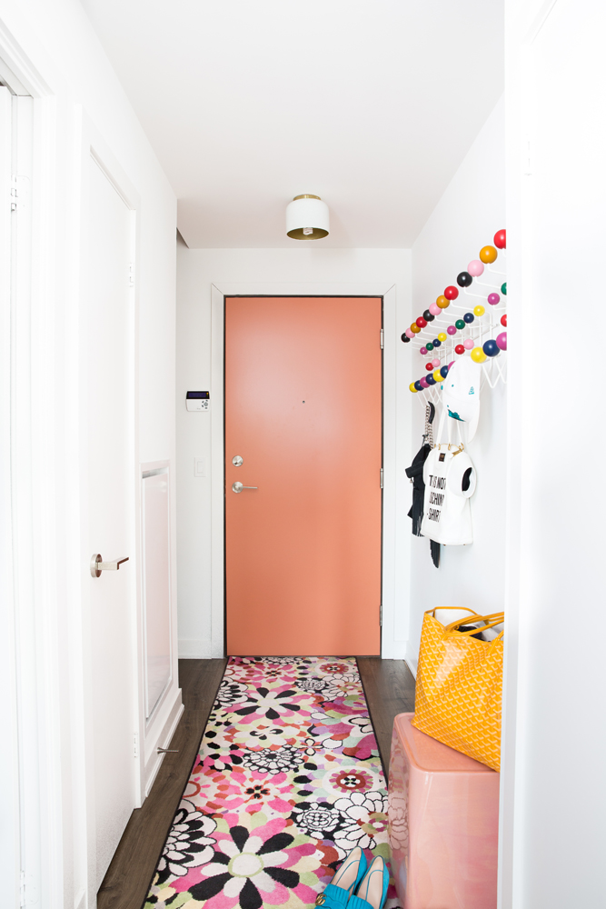 Pink-painted door with flowery rug in foyer