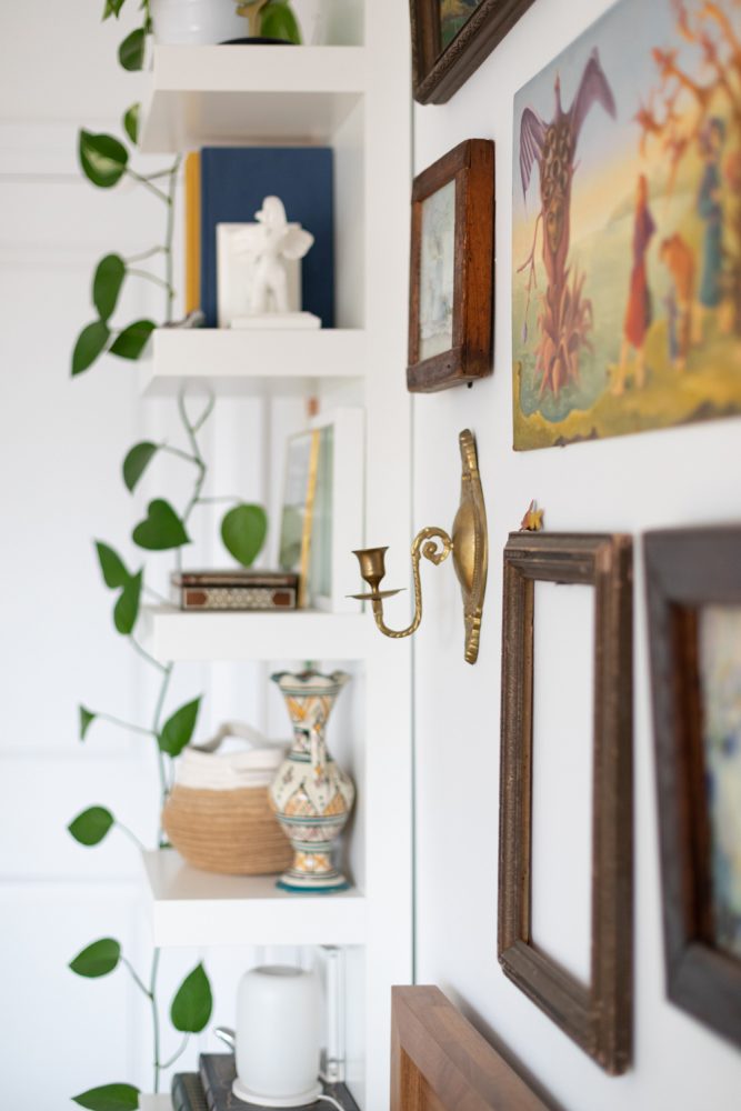 Close-up of white shelves and gallery wall above bed