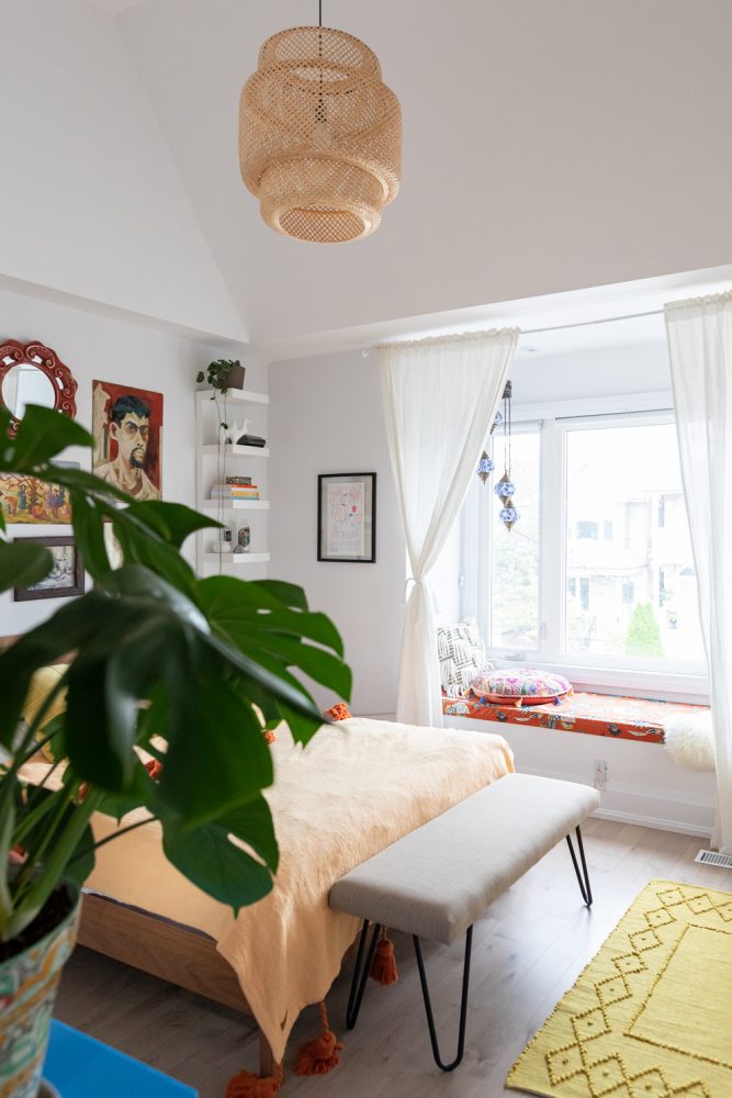 cozy white bedroom with woven hanging light fixture over bed