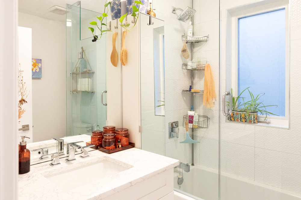 White bathroom with glass shower door and green plants