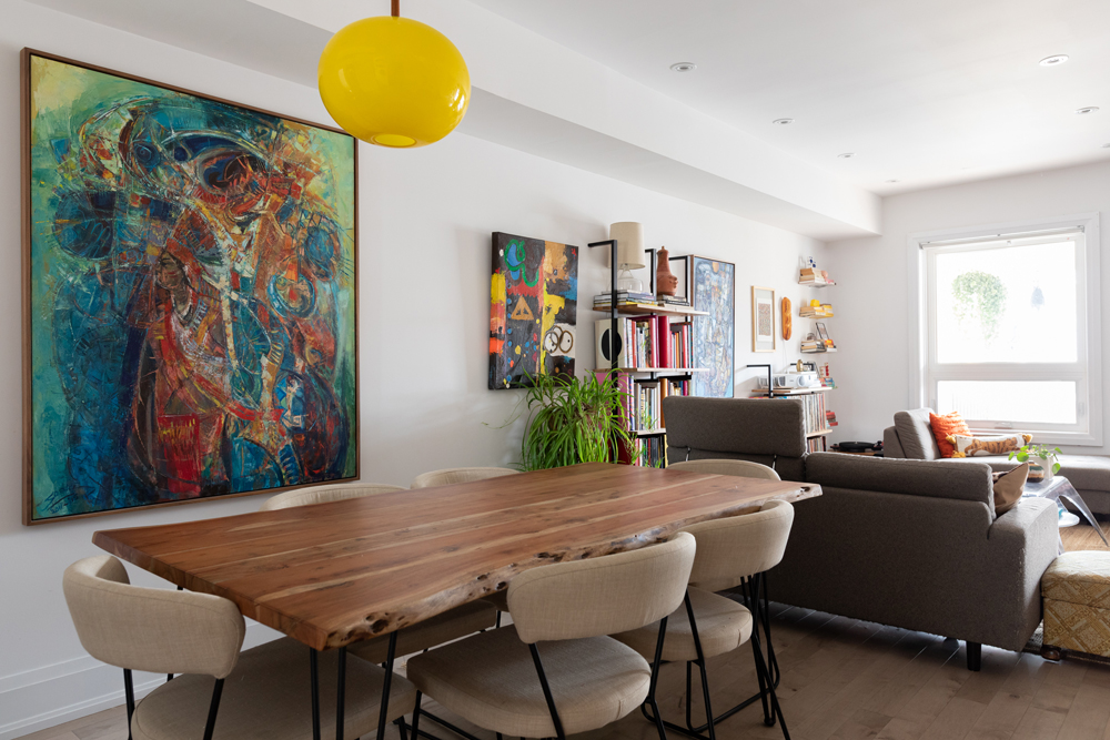 White dining room with wood table and yellow hanging light