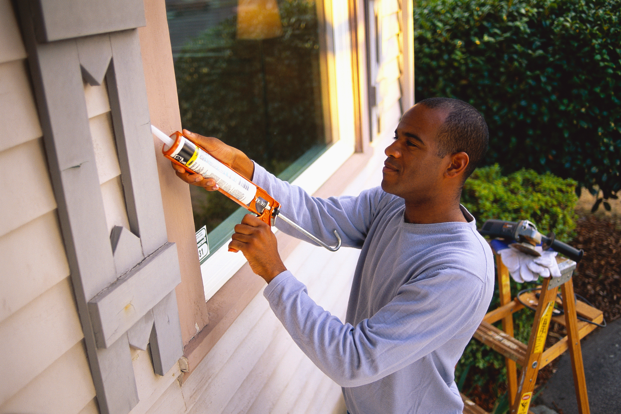 Man checking caulking on window