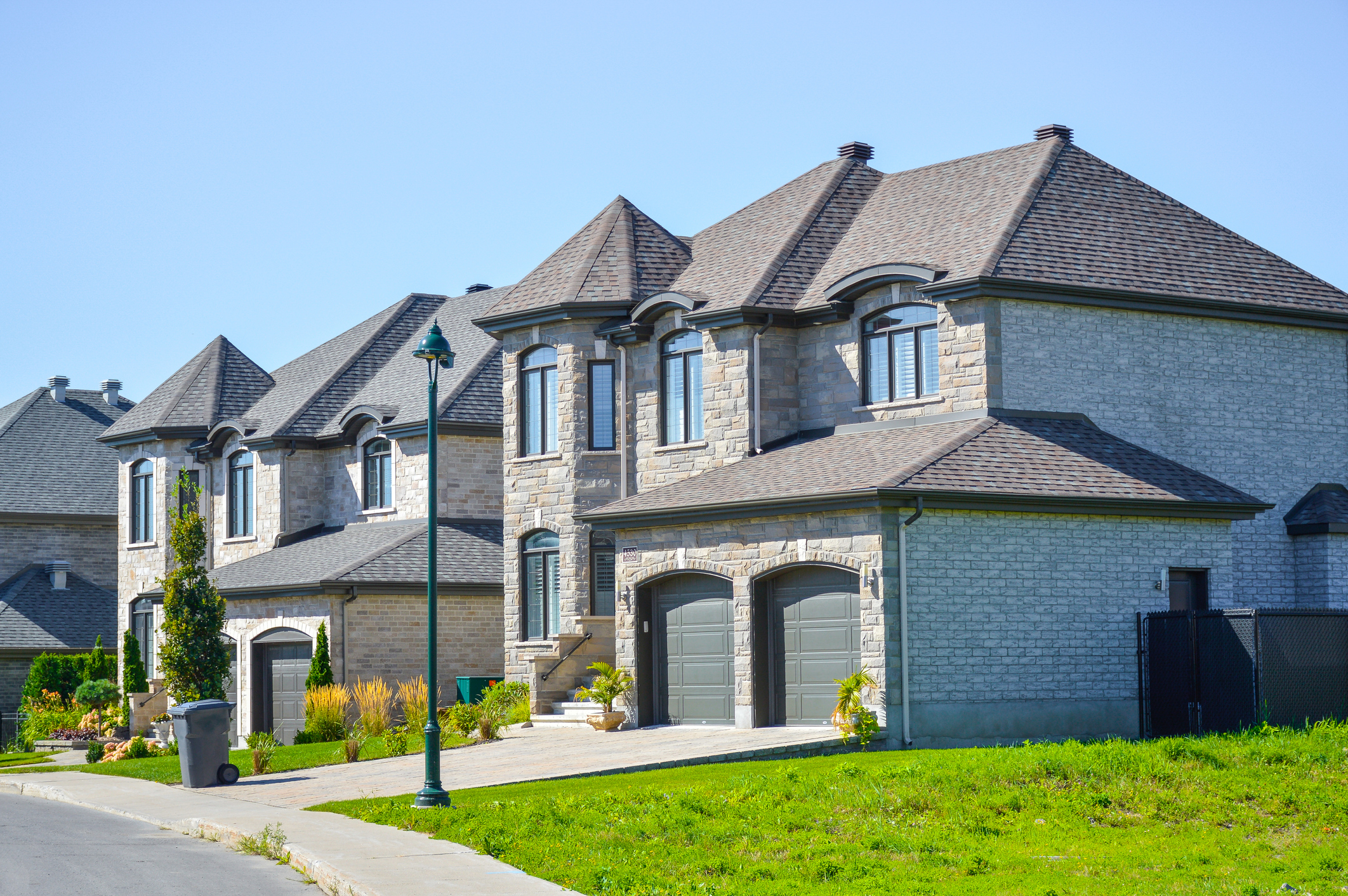 A grey, multi-story, two door garage home.