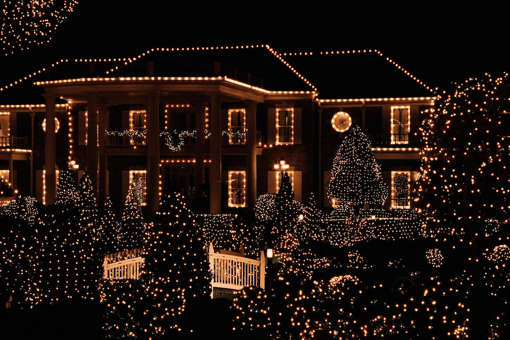 house with white holiday lights on the house and trees in front yard