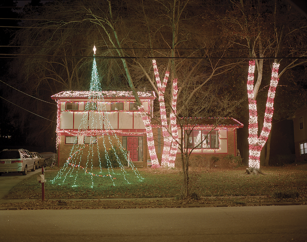 white and brick house with red-and-white lights on the roof and front