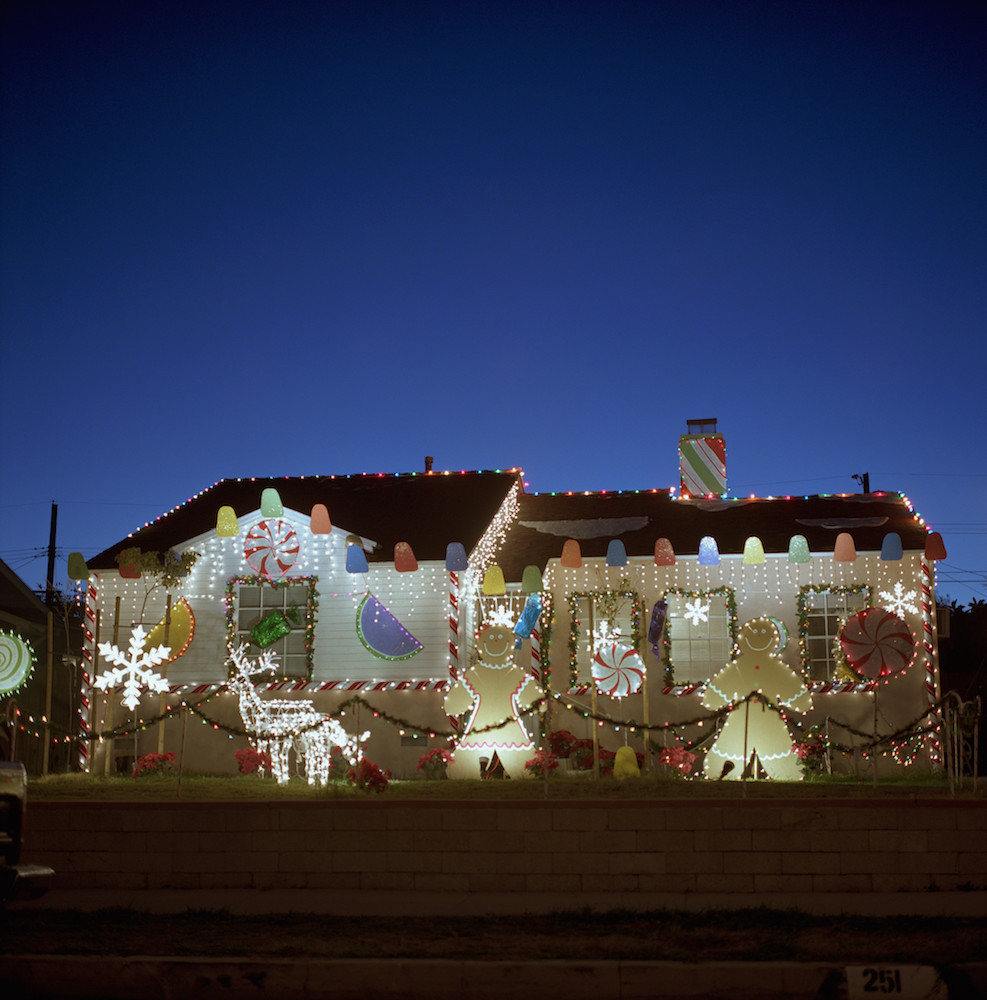 white house decorated with candy-themed Christmas lights at night