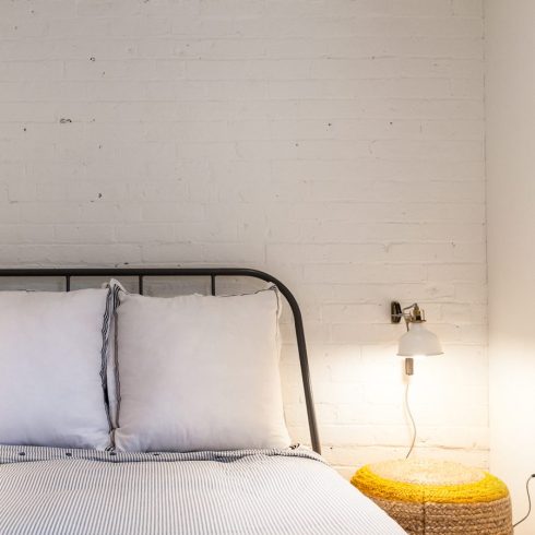 A brick wall in a basement bedroom that is painted white