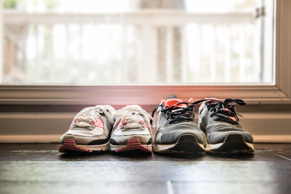 Two pairs of sneakers on a tile floor