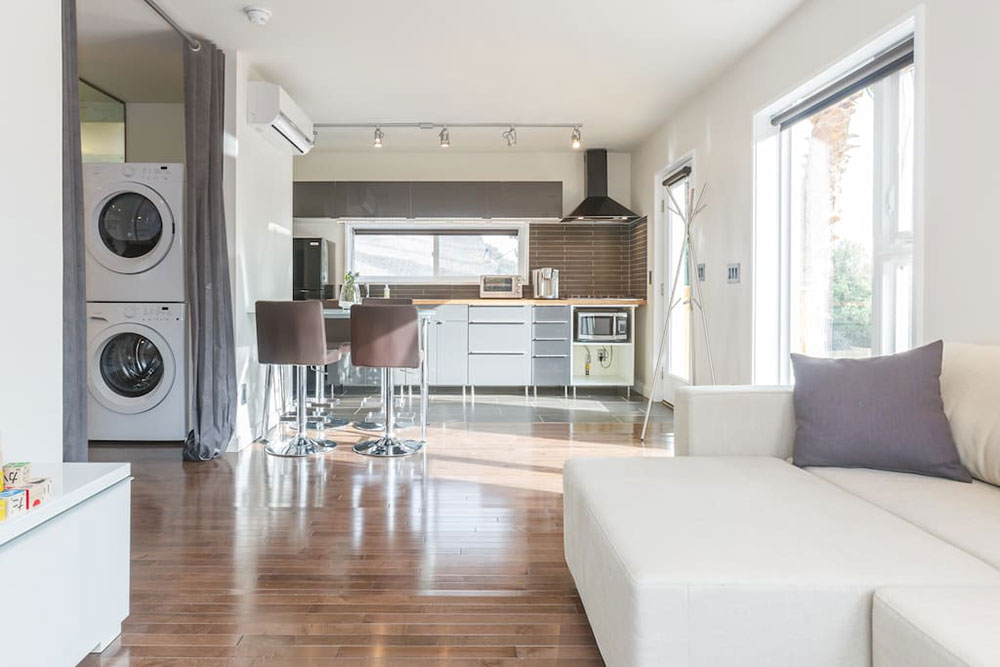 Interior of the storage container home with wood siding, which features living space, kitchen and washing machine