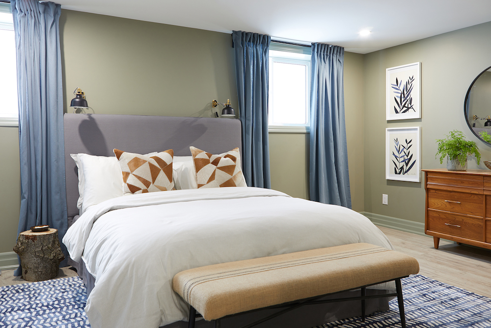 Basement bedroom with full-length curtains and large bed with bench and decorative accessories