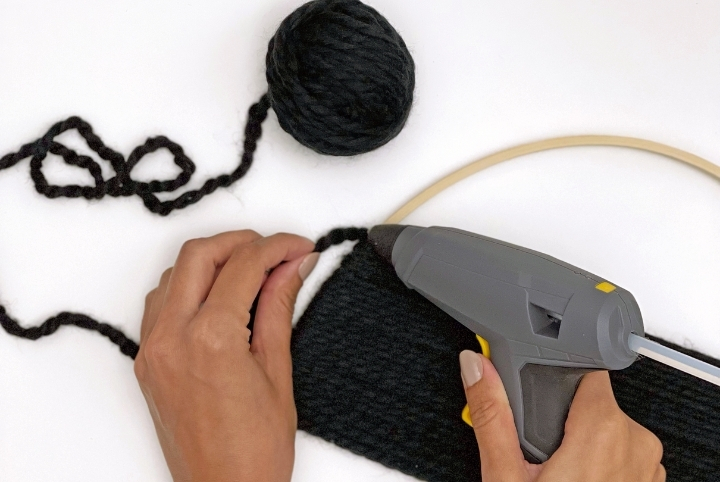 Creating a stylish wall decor DIY art piece with a glue gun and yarn