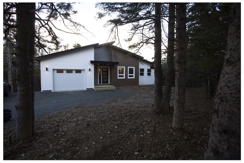 white house in the woods with angled roof