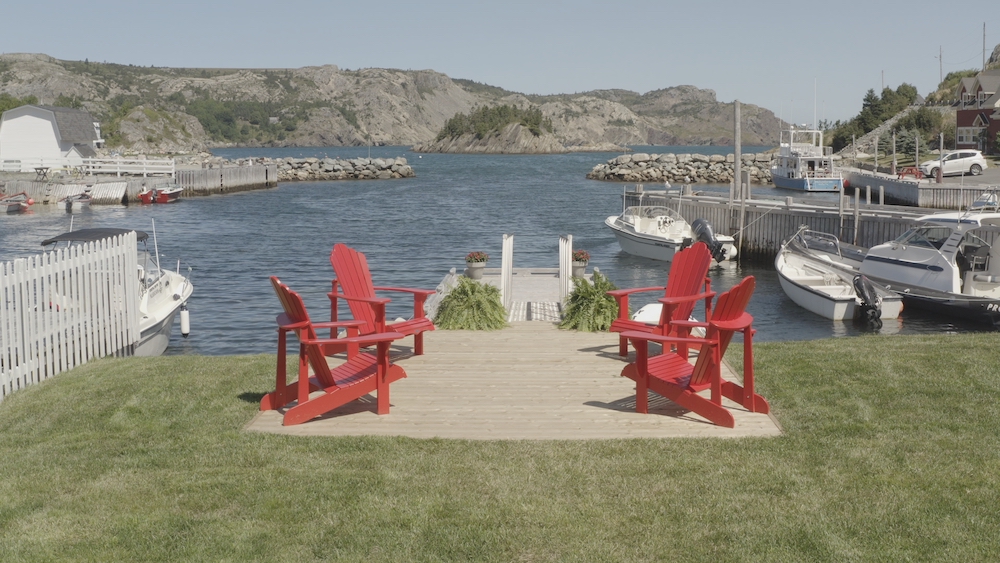 view of ocean from wooden dock with four red chairs