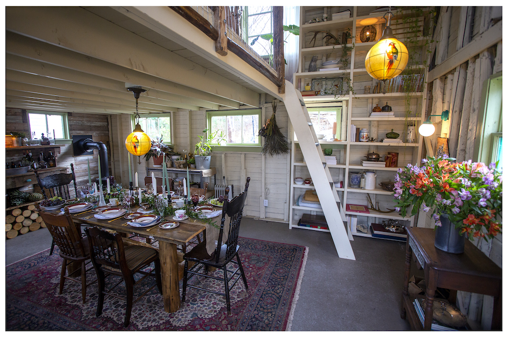 open barn dining area with ladder leading up to loft and floor-to-ceiling bookshelf