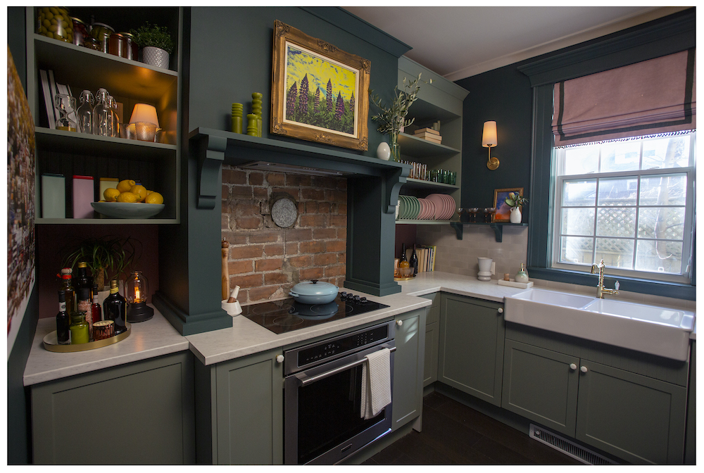 green kitchen with exposed brick behind stove