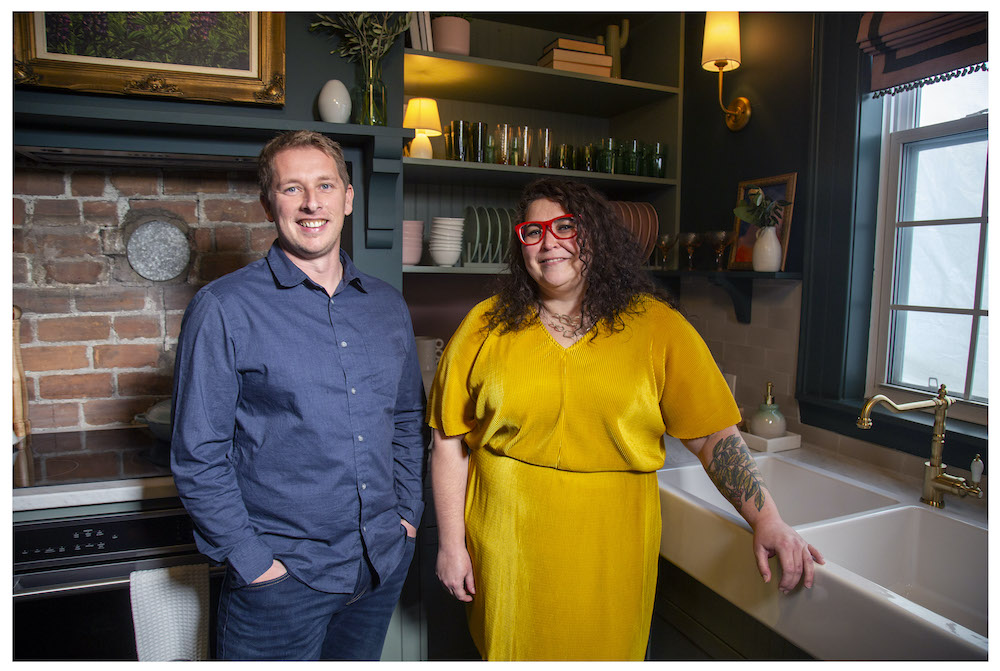 Randy and Krista in green kitchen with exposed brick