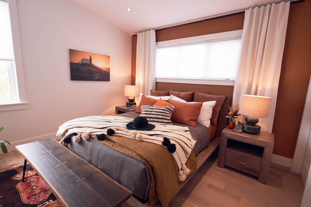 cozy master bedroom with brown feature wall, wood bench and layered bedding