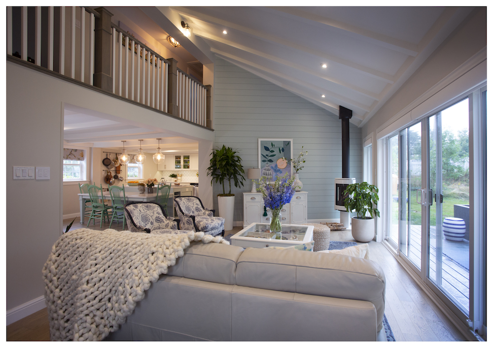 pale-blue living room with stair railing above, comfy couch and modern black fireplace