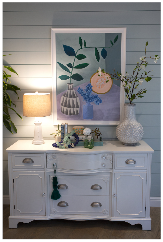 blue living room wall with styled white cabinet and colourful wall art