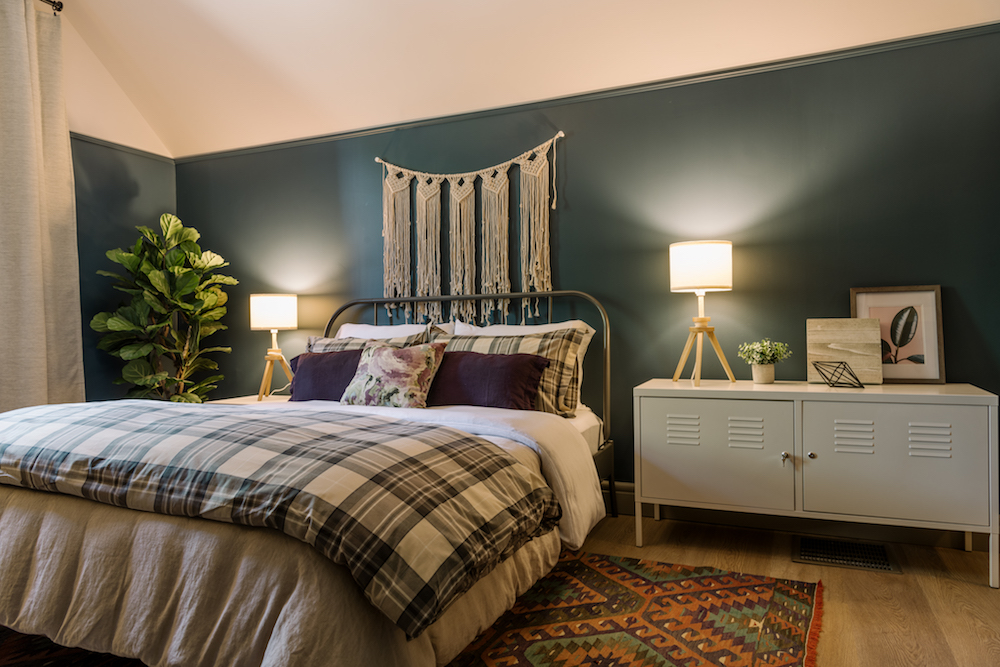 dark green bedroom with plaid bed and white wall hanging