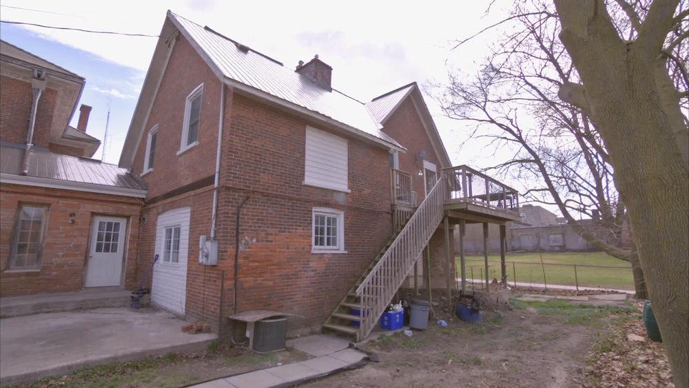 exterior of run-down brick carriage house