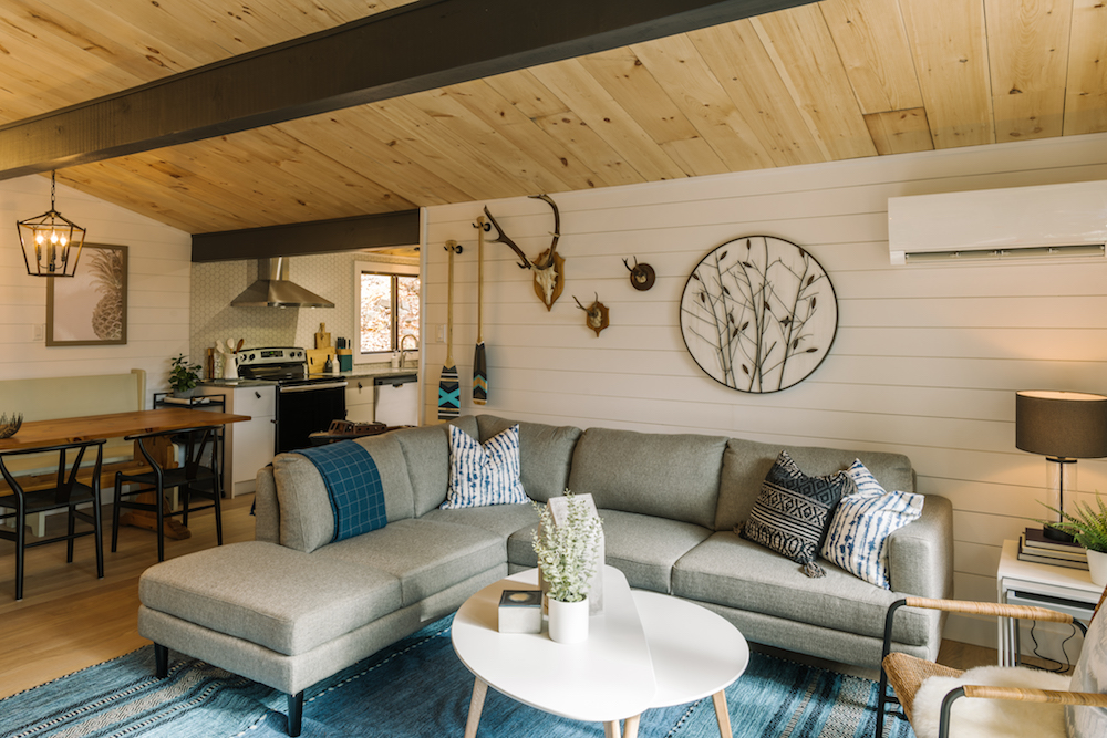 modern white living room with grey couch and wood ceiling