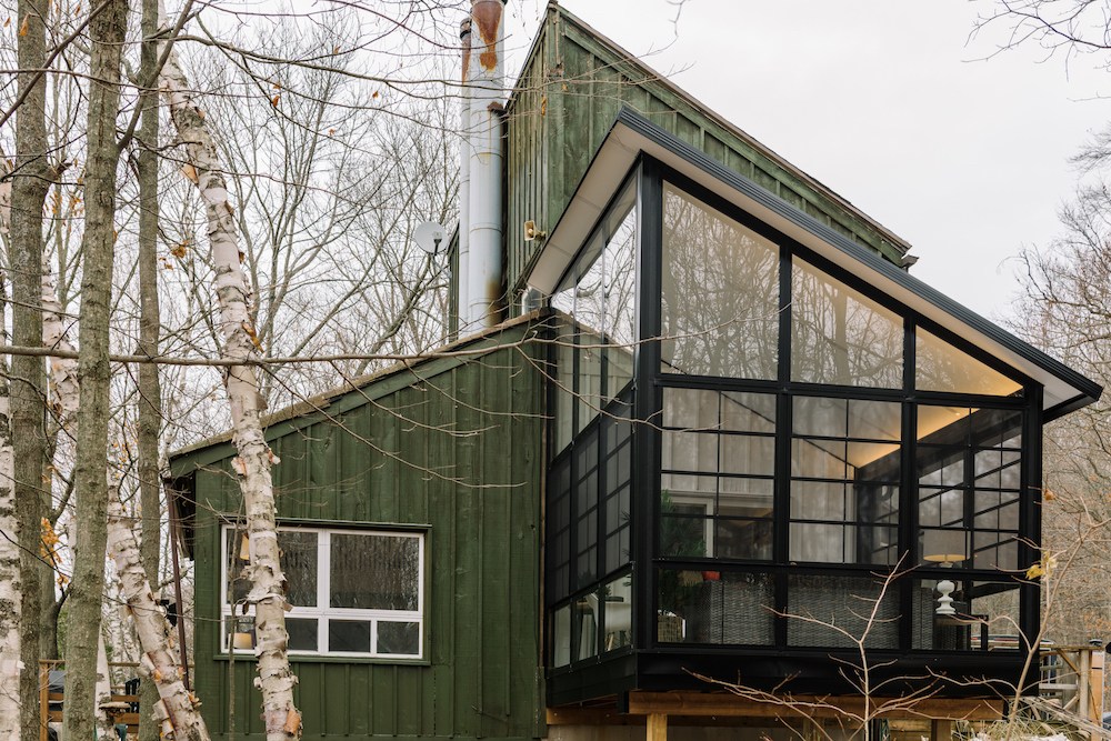 green cottage exterior with glass sunroom addition