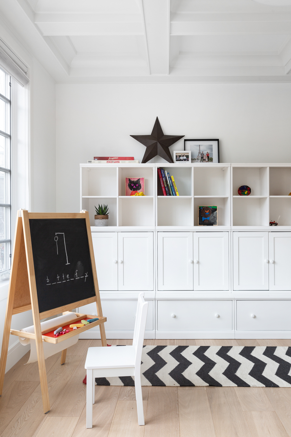 Stylish playroom area in living room showing bookshelves and children's art easel