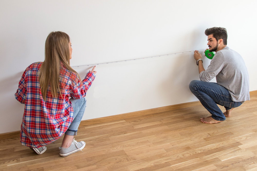 Couple measuring a wall