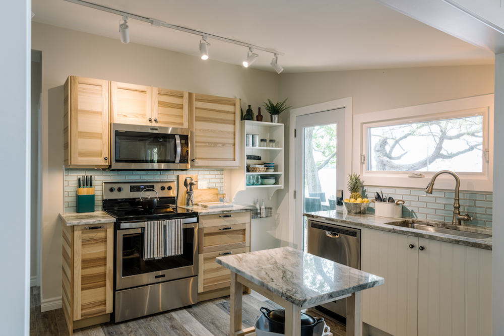 modern beach house kitchen with wooden cabinets, window over sink and stainless steel appliances