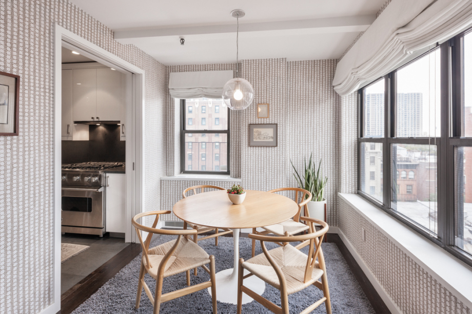 wooden dining table in wallpapered dining room with windows