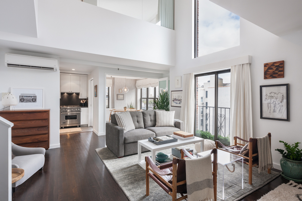 grey couch and brown chairs in white living room with high ceiling