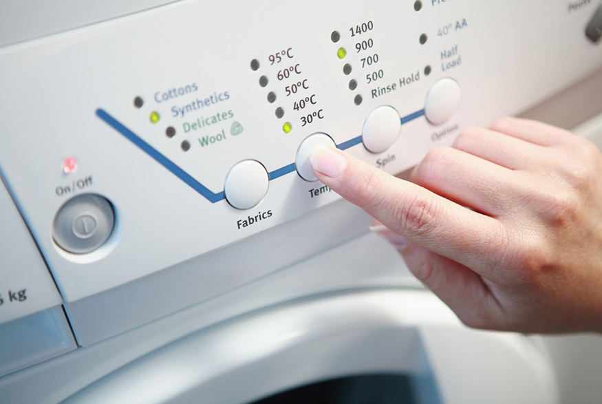 Woman turning washing machine to cold water