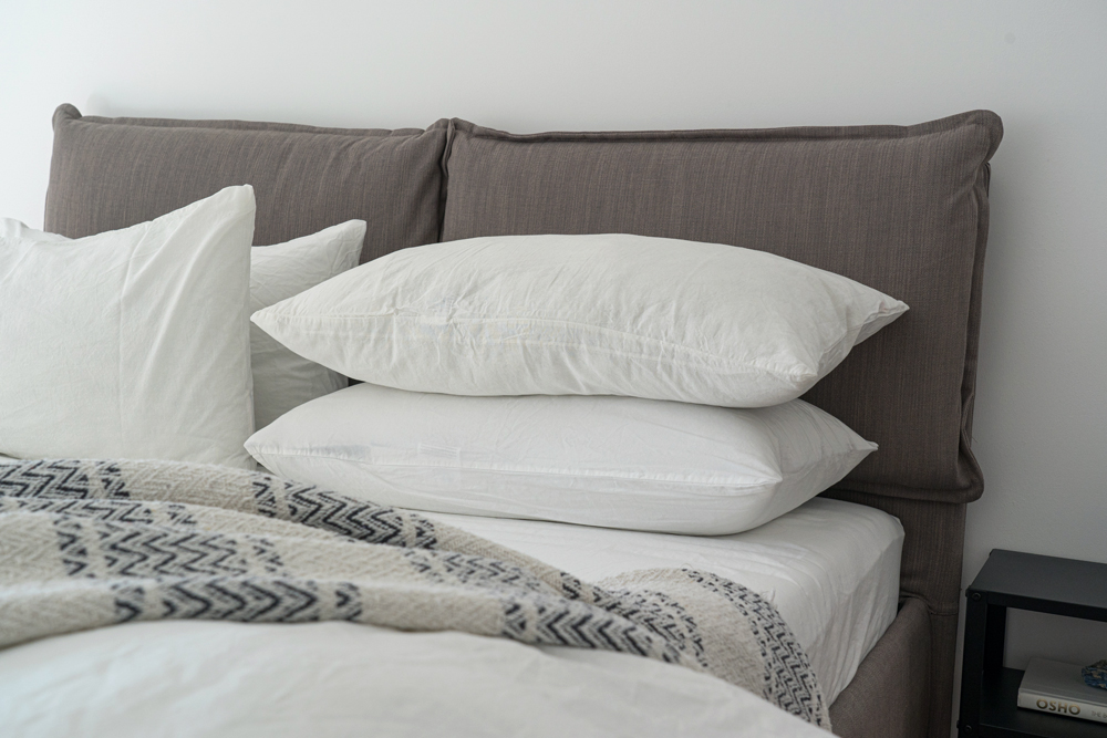 a close-up shot of a neatly made bed with white sheets and a woven blanket