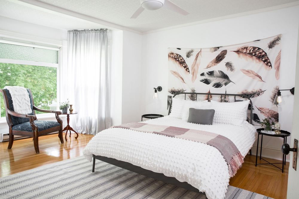 A sleek white bedroom with leggy furniture, from the bed to the chairs