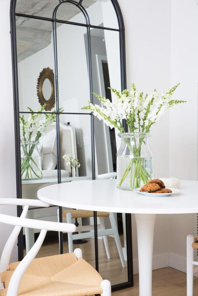 A floor-to-ceiling bedroom mirror with a table in front