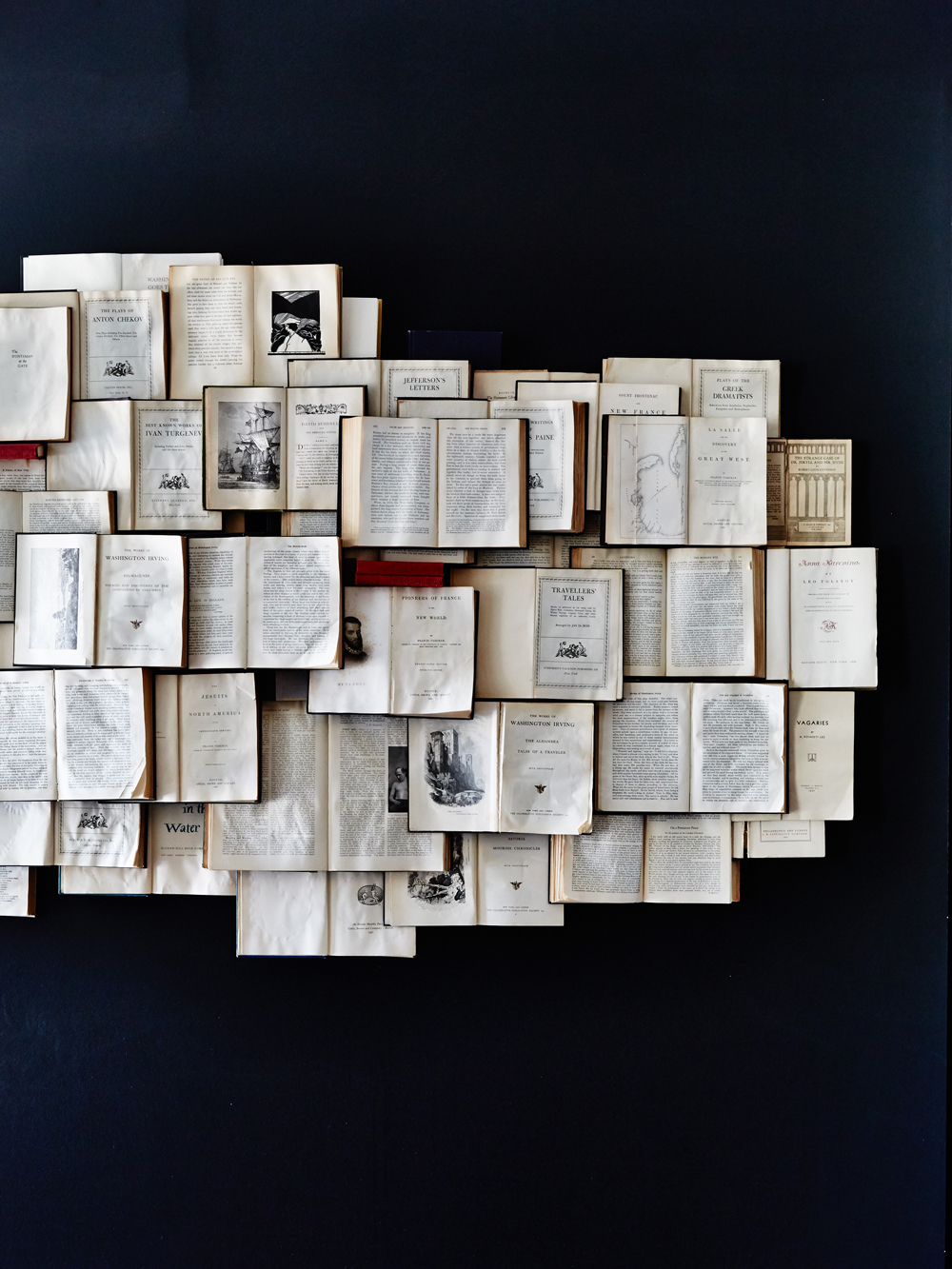 A dark blue wall featuring a layered book wall art display