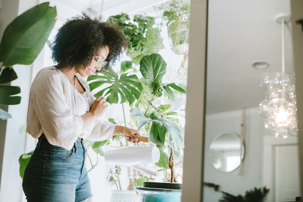 Young woman waters houseplants