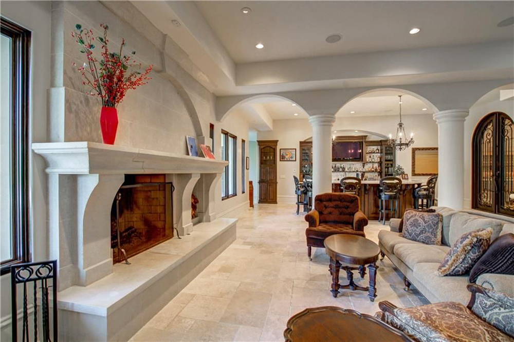 A lounge area with a stocked bar off to the right and a wood-burning fireplace in front of the couch