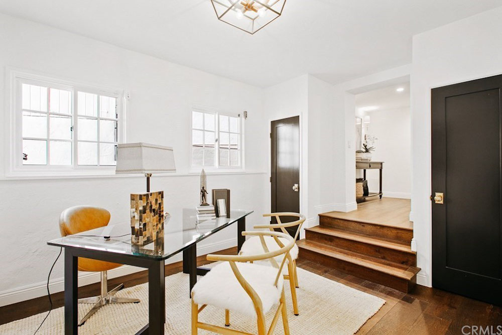 A sunken home office with a glass-topped desk and plush chairs