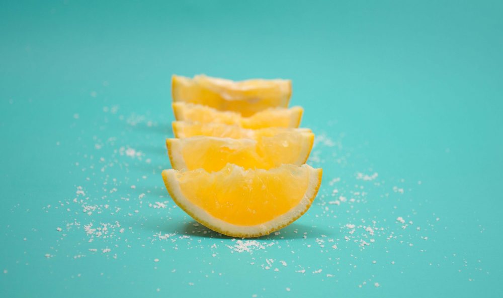 A row of sliced lemons and salt against a pastel blue background